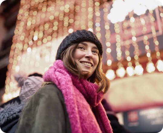 Imagen de una joven con gorro y bufanda en ambiente navideño